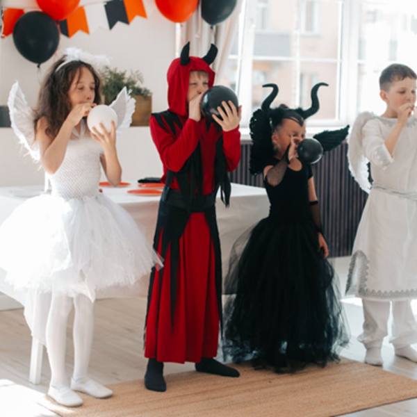 4 Kinder in unterschiedlichen Kostümen zwei tragen Engel Kostüme und zwei tragen ein Teufel Kostüme