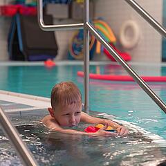 Kind schwimmt auf Trainerin zu