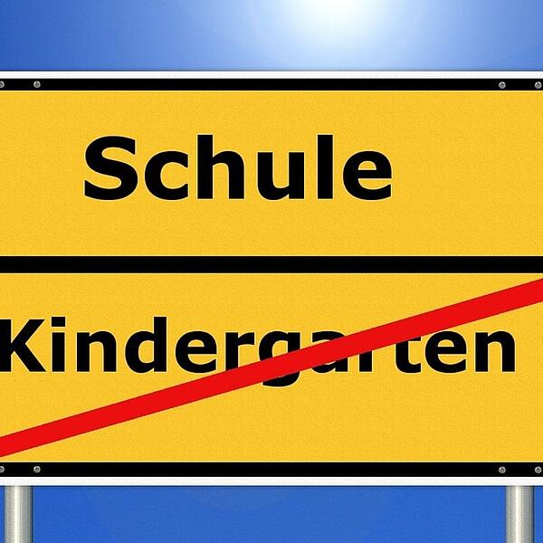 Schulbeginn Ortsschild mit Schule und Kindergarten durchgestrichen
