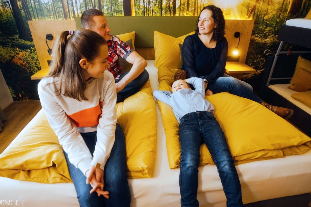 EIne Familie sitzt und liegt gemeinsam auf einem Bett