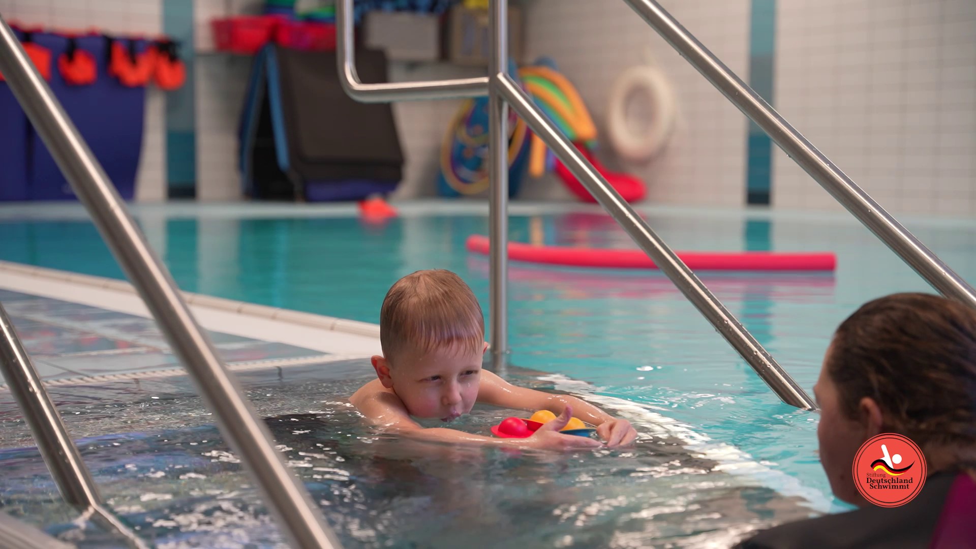 Kind schwimmt auf Trainerin zu