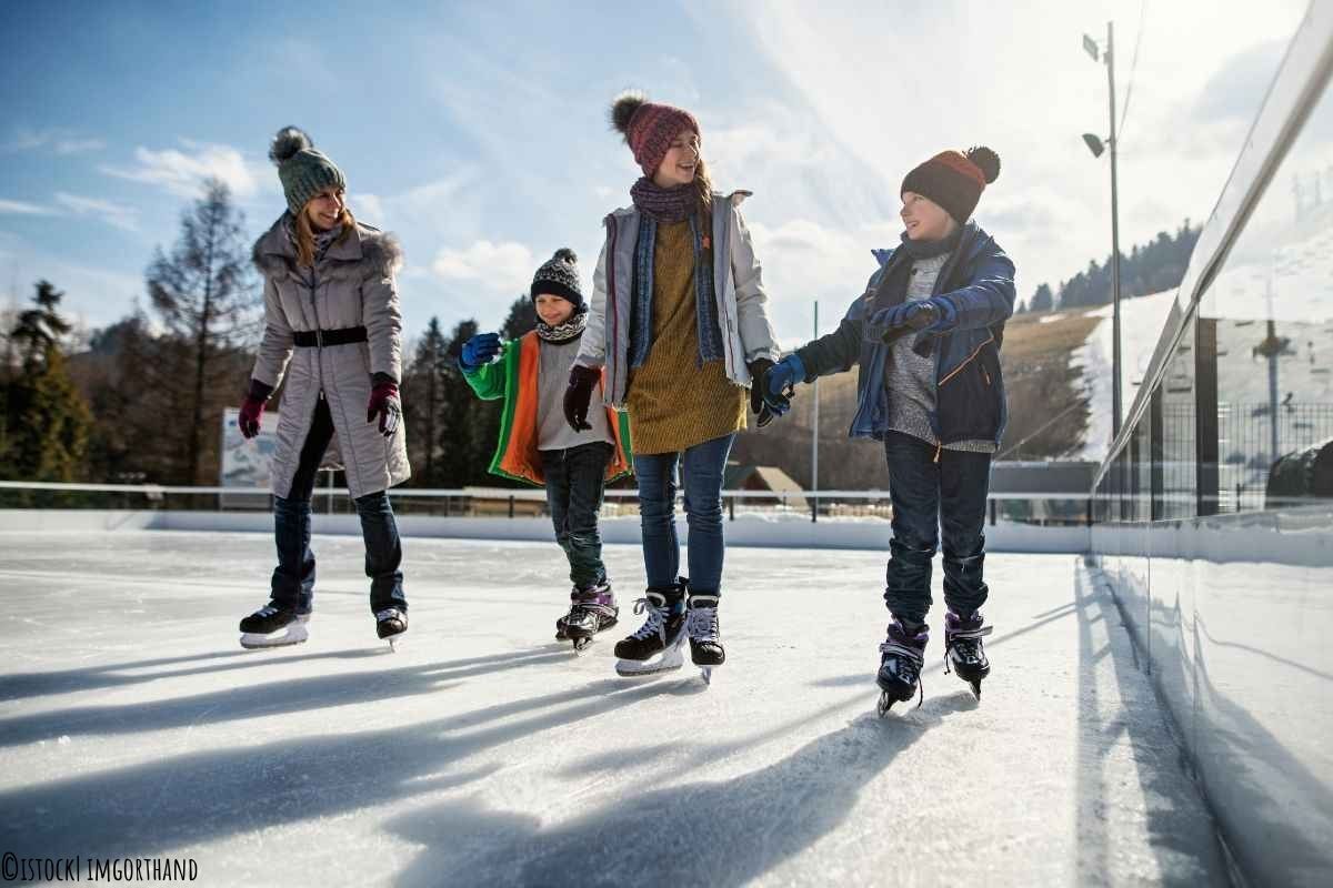 Mutter geht mit drei Kindern zusammen Eislaufen