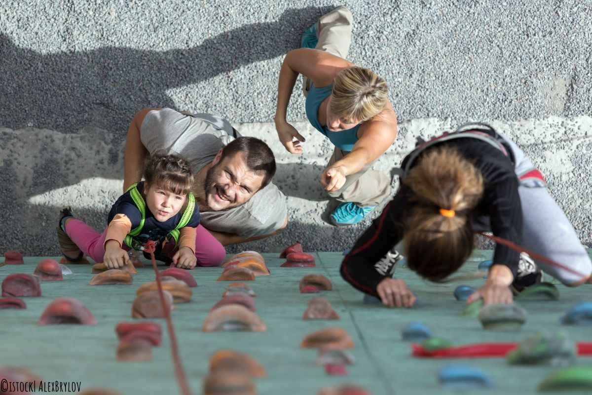 Familie klettert gemeinsam eine Kletterwand hoch