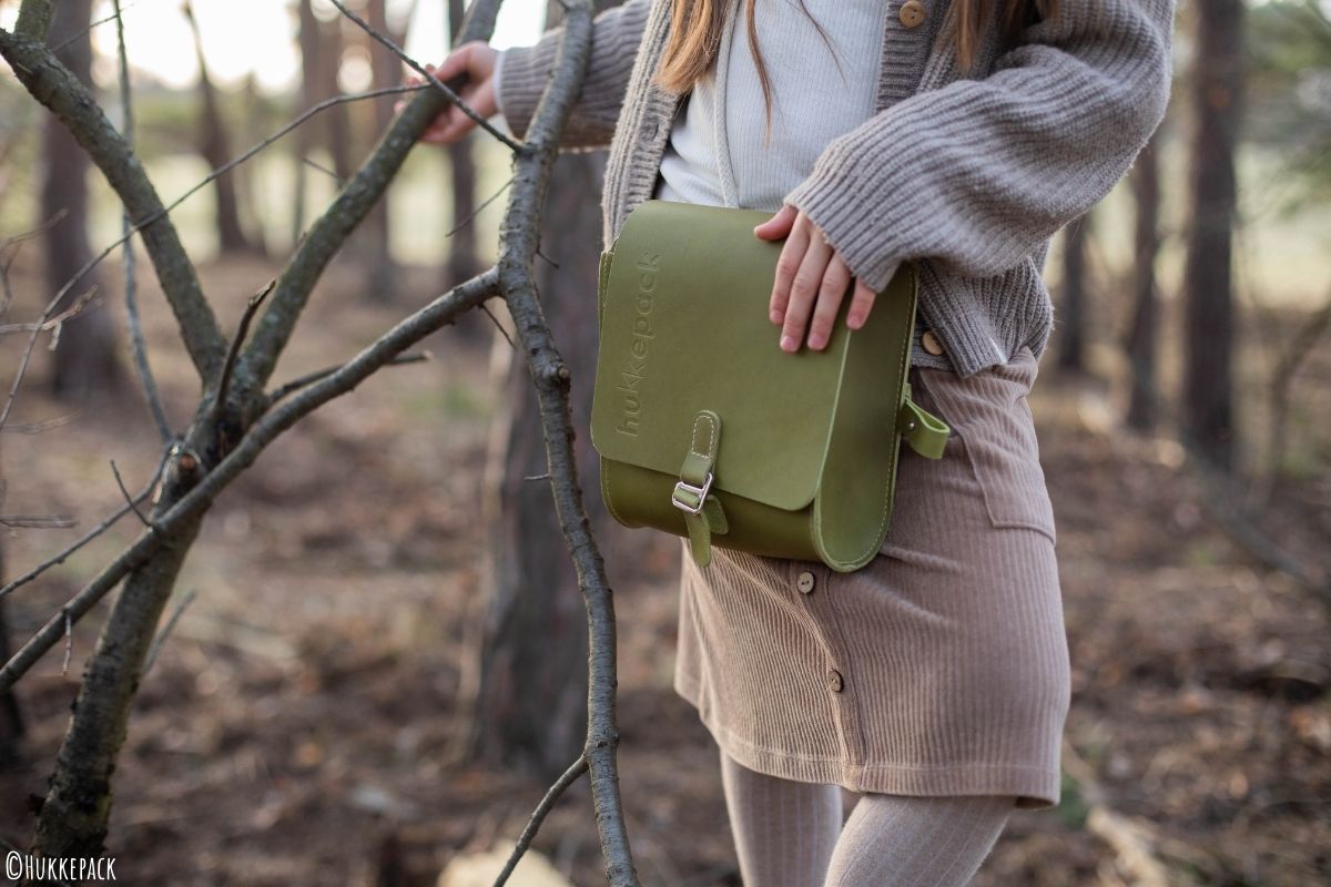 Kleiner Grüner Rucksack wird von einem Kind gehalten