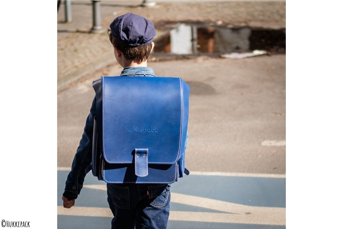 Junge mit blauem Rucksack spaziert